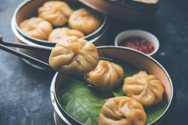 Momos népalais à la sauce achar dans un bol avec des baguettes